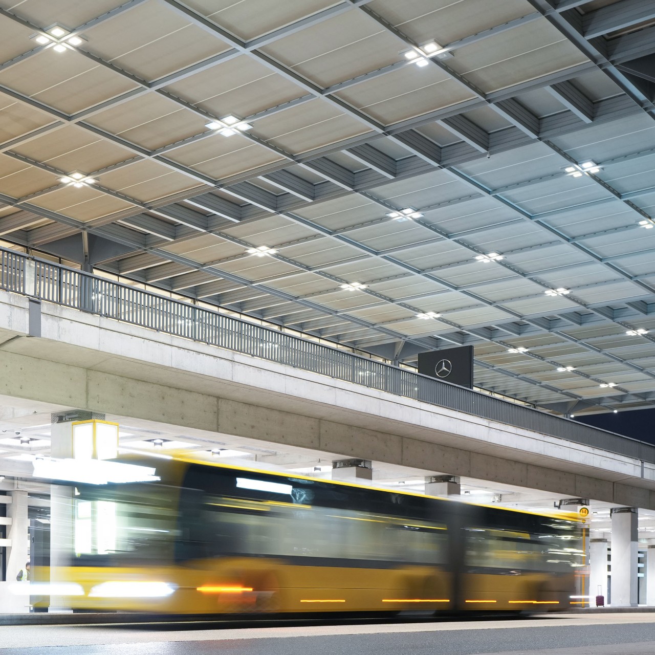 Blurred image of a bus. Behind it the roof of Terminal 1
