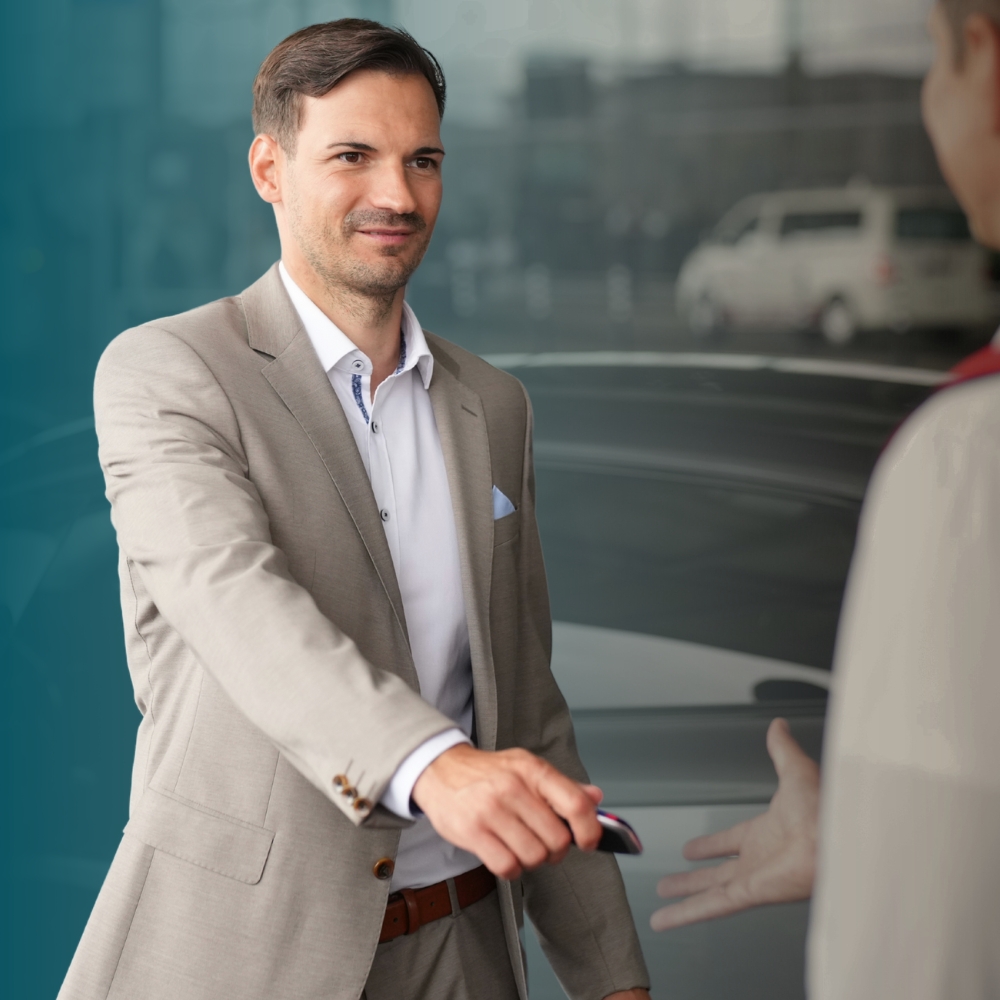 Man hands over his car key to valet employee in front of Terminal 1, informing him that this is a new service that can be booked.
