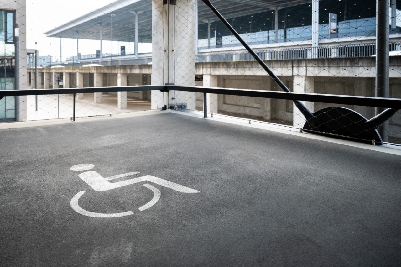 Wheelchair pictogram in a parking lot, Terminal 1 in the background