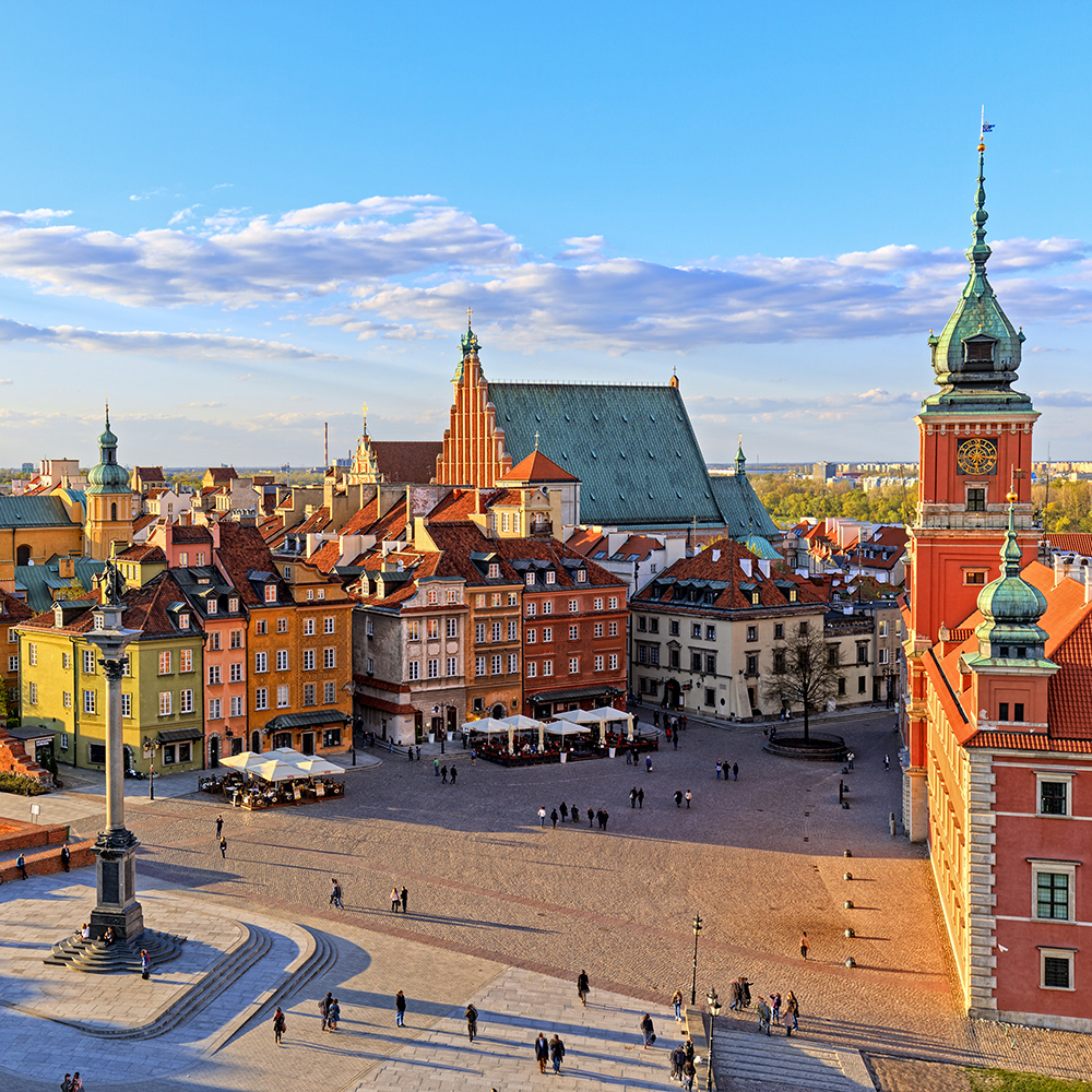 Blick von oben auf Warschaus Innenstadt mit eleganten Häusern, Kathedrale und einem belebten Platz.