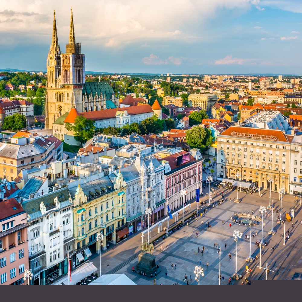 Blick von oben auf Zagrebs Innenstadt mit eleganten Häusern, Kathedrale und einem belebten Platz.