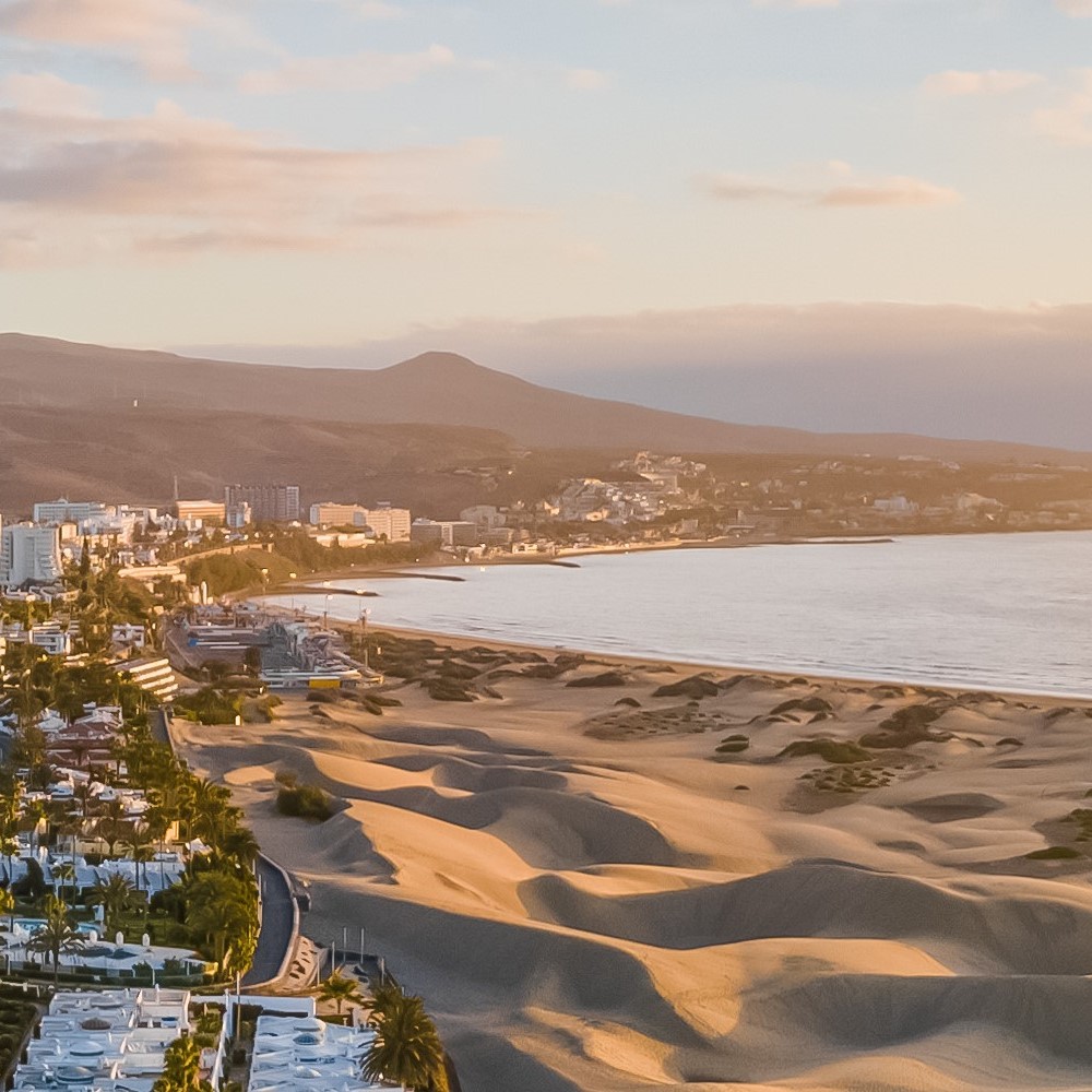 Bay with a dune-like beach and white houses in the soft evening sunlight