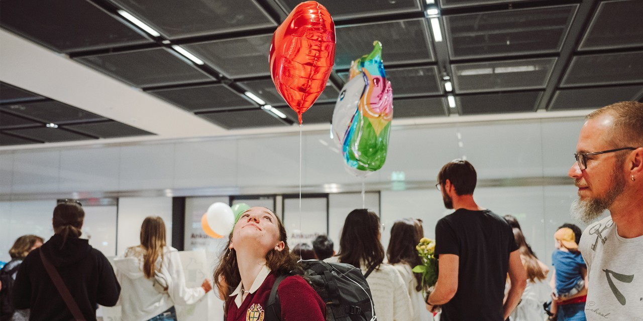 Gelen yolcuları bekleyen karşılama personeli. Bir kişi 2 balon tutar.