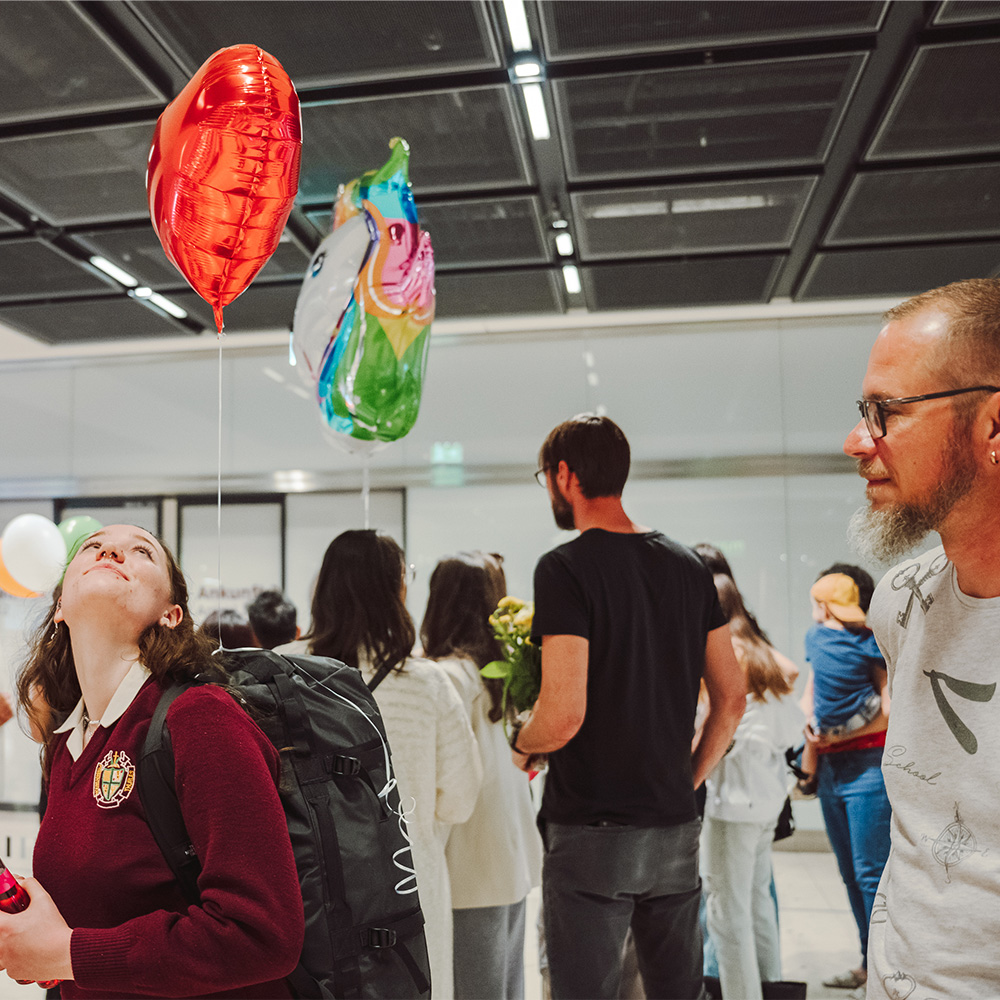 Gelen yolcuları bekleyen karşılama personeli. Bir kişi 2 balon tutar.